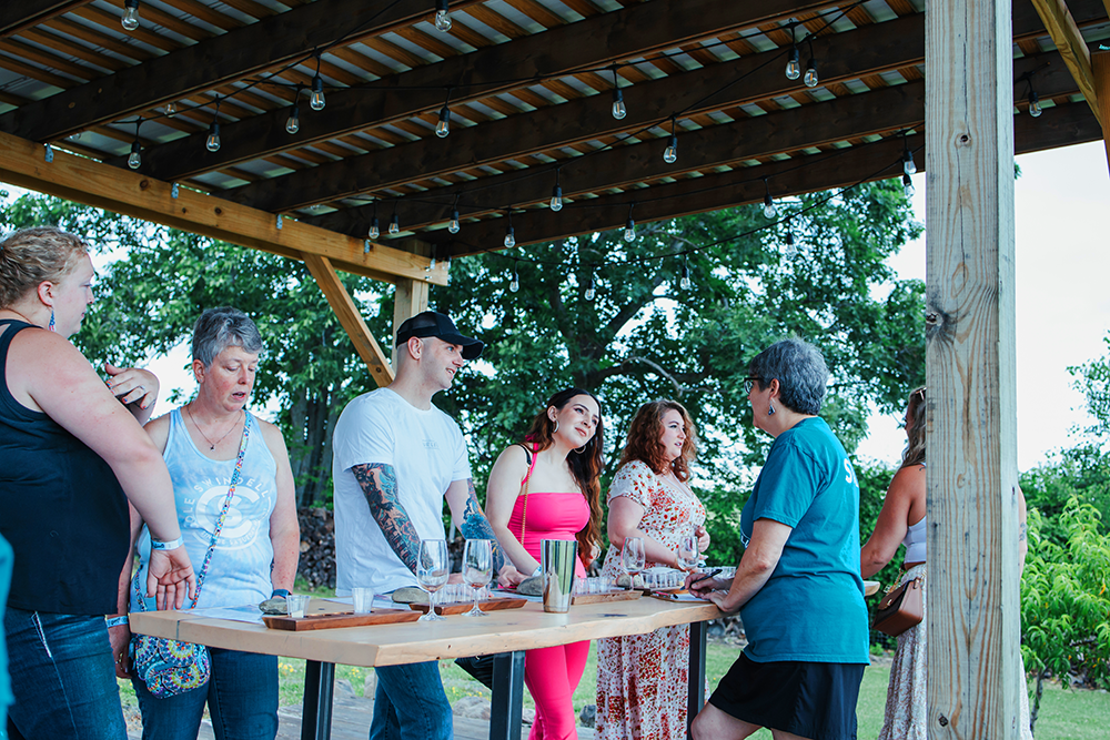 image of group of people enjoying a wine tasting under the pergola at the concert venue