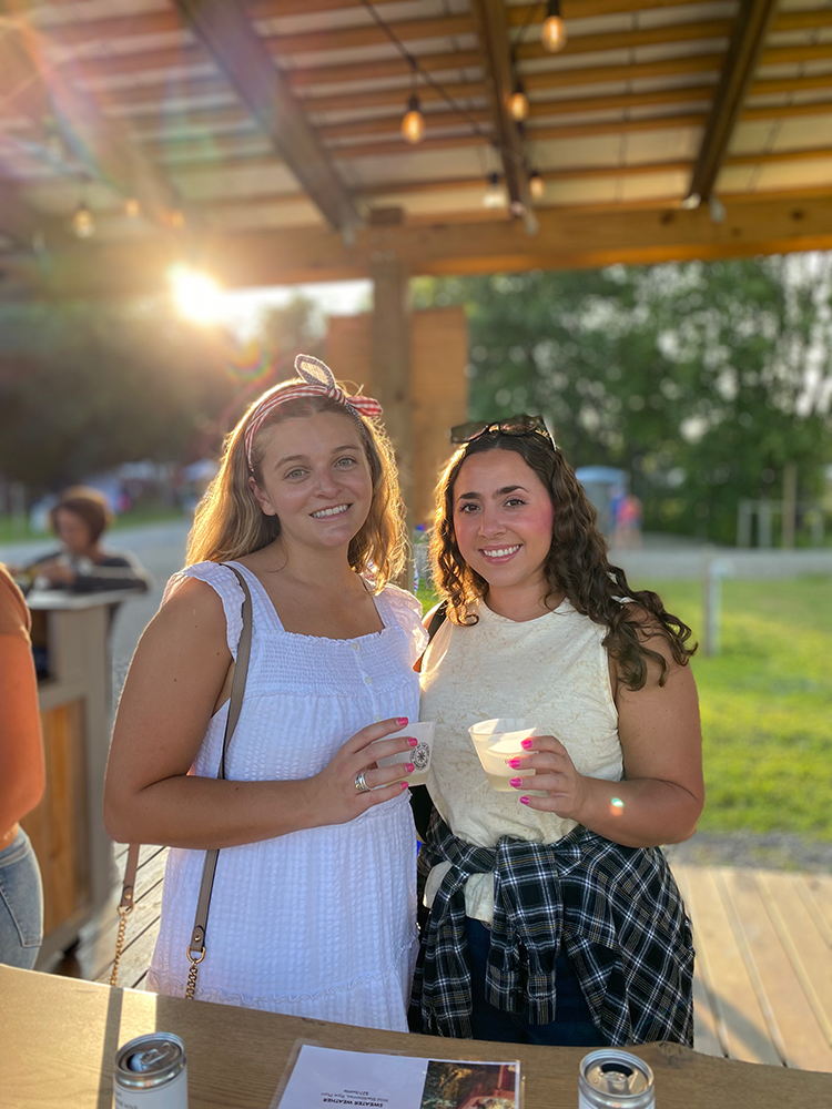image of two women enjoying a wine tasting under the pergola at the concert venue
